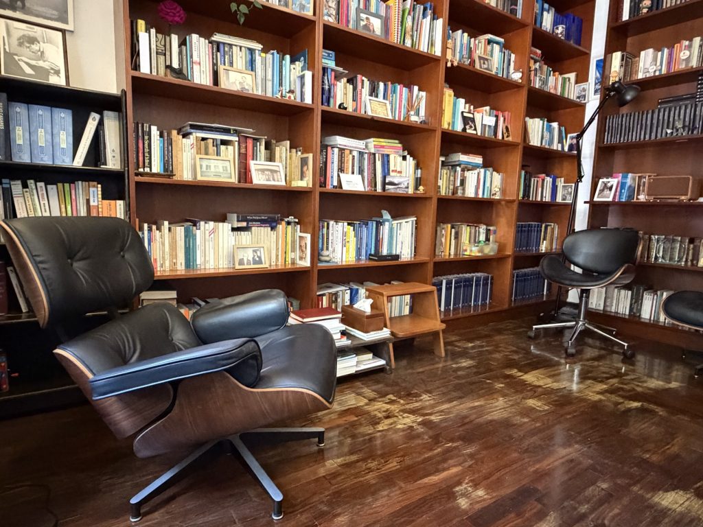 Consultorio de Ernesto Reaño, con biblioteca de madera y sillones.