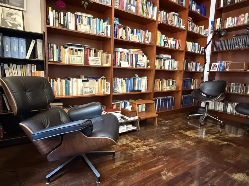 Consultorio de Ernesto Reaño, con biblioteca de madera y sillones.